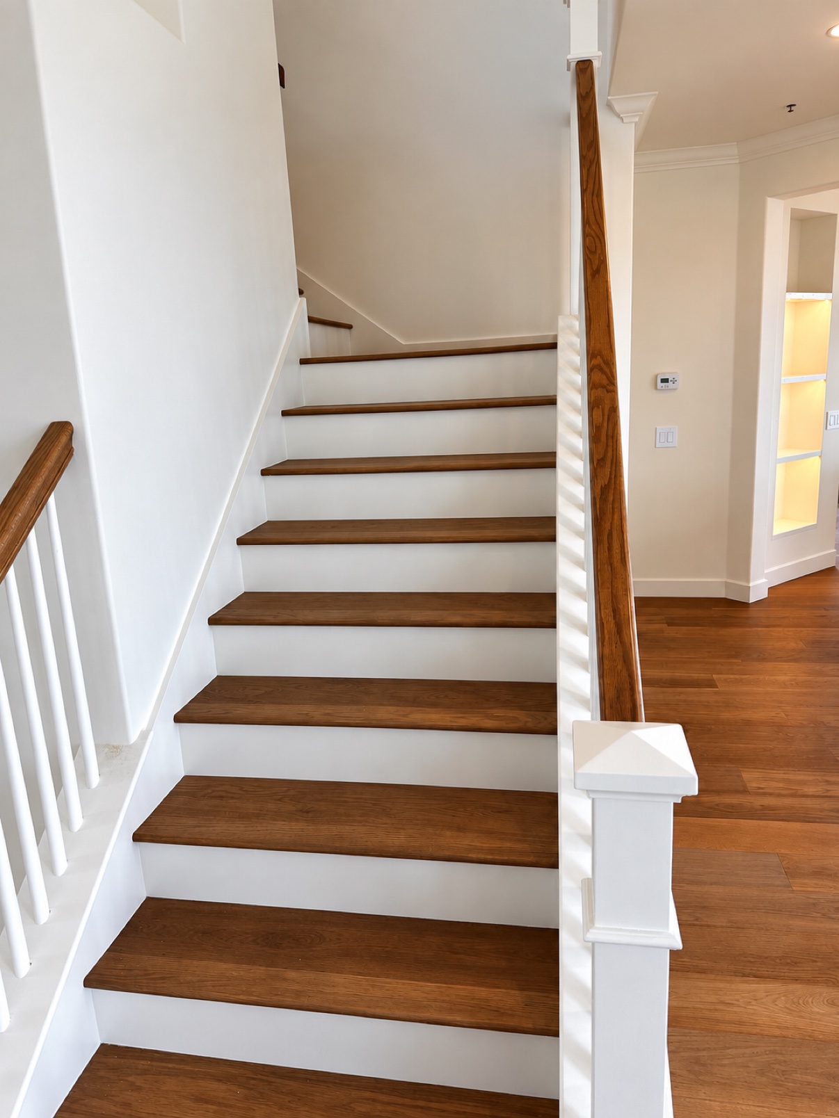Finished staircase with wood treads, white risers, and wood railing